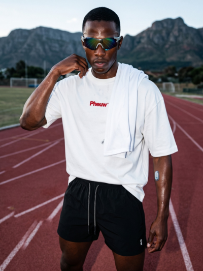 Athlete wearing black woven quarter shorts and a white Pheuw tee on a running track